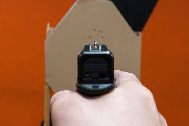 Close-up POV of aiming a black pistol at a shooting target. Rear sight in sharp focus.