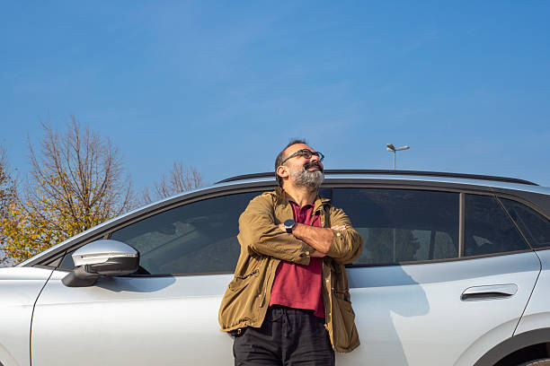 istock Cheerful man standing by a car and smiling 2245159071
