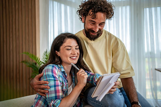 Mid adult man surprising his mid adult wife while she works from home, presenting her with a stunning bouquet of pink roses, creating a moment filled with love and joy