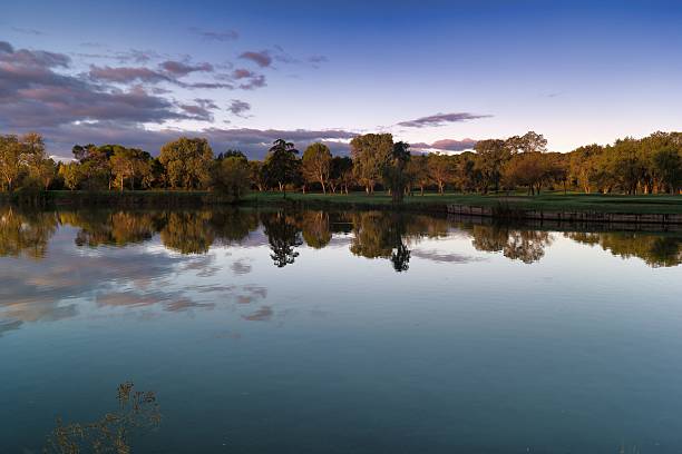istock Calm reflection of trees and clouds on a serene lake during sunset 2245162547