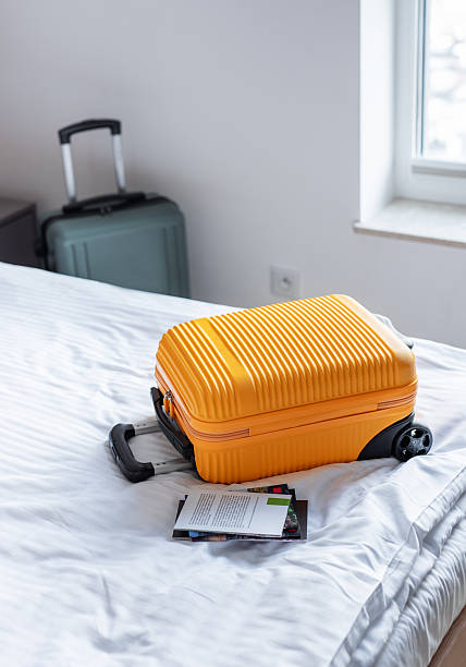 istock Orange suitcase on hotel bed welcoming travelers arrival 2245163247