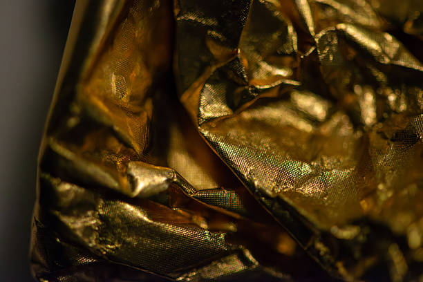 Close-up abstract shot of crumpled aluminum foil creating a textured surface. The metallic silver and dark contrasts create a dynamic pattern suitable for backgrounds or graphic elements. The image evokes a sense of industrial texture and raw material.