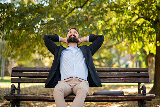 Smiling businessman listening music with eyes closed while relaxing in the city.
