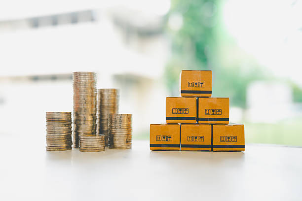 istock Stacked coins beside cardboard parcel boxes on white background, symbolizing shipping costs, e-commerce investment, logistics budgeting, and financial planning in retail business. 2245166065