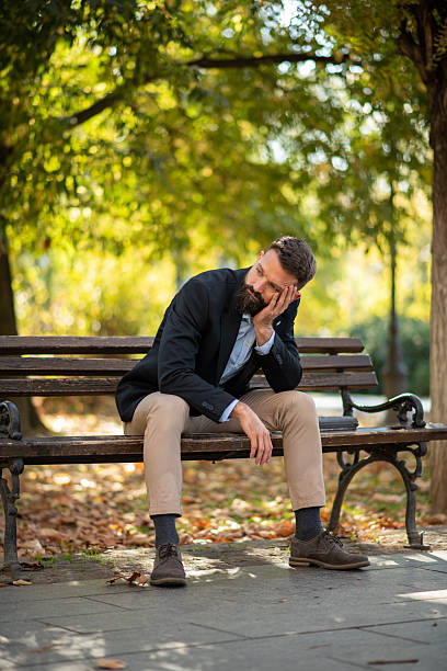 istock Frustrated man sitting on park bench 2245166114