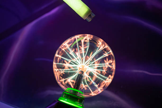 istock A fluorescent tube held near a plasma ball begins to glow. This physics experiment demonstrates wireless power transfer and the excitation of inert gas by a high-frequency field. 2245167966