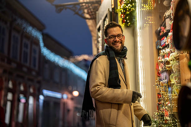 istock Man smiling window shopping during christmas holidays at night 2245170476