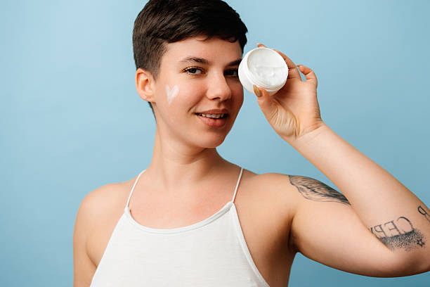 istock Smiling woman applying face cream, skincare routine 2245174403