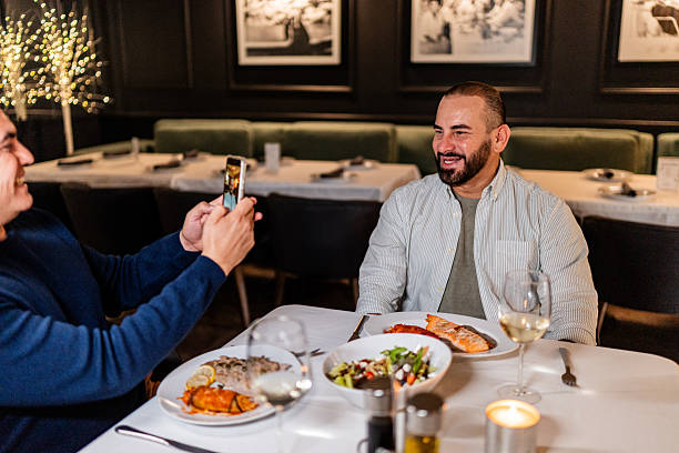 Mature man photographing husband at restaurant