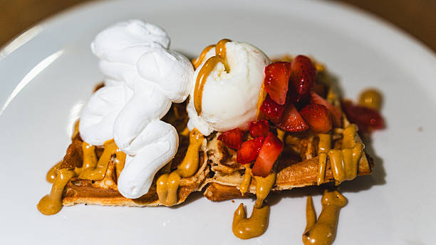 Crispy waffle topped with vanilla ice cream, fresh chopped strawberries, delicious syrup, and marshmallow. A perfect dessert for sweet cravings and cafe menus.
