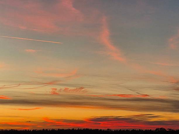 A vivid ethereal cloud scape with the setting sun emitting its light forming orange, pink and purple clouds against the blue sky