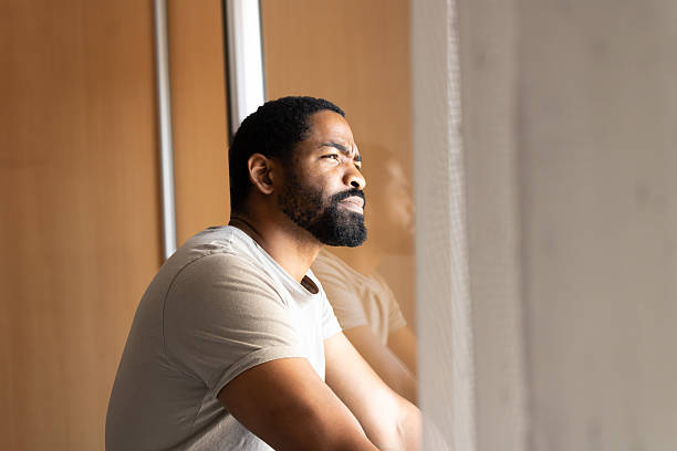 istock Man alone looking out window feeling pensive and worried 2245180476