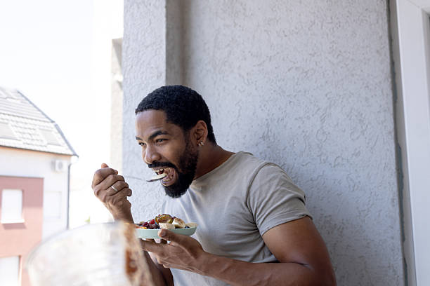 istock Man enjoying healthy fruit salad breakfast on balcony 2245180568