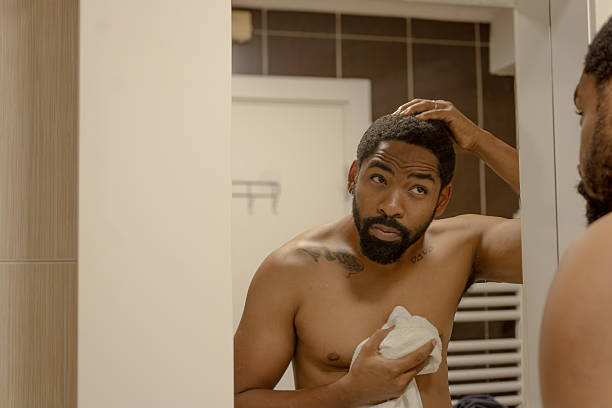 istock Man checking hair in bathroom mirror reflection 2245180695