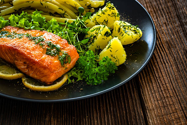 Seared salmon steaks with  string beans and boiled potatoes on wooden table