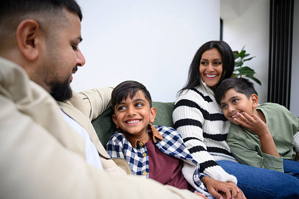 British Asian parents and two sons relaxing on living room couch, bonding, love, togetherness