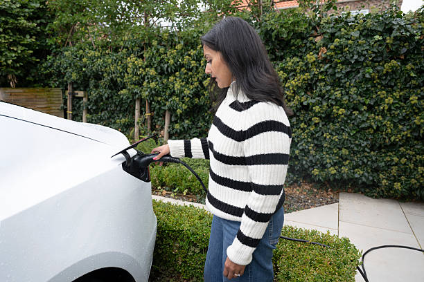 istock Woman holding charging cable and charging EV at home on drive 2245182469