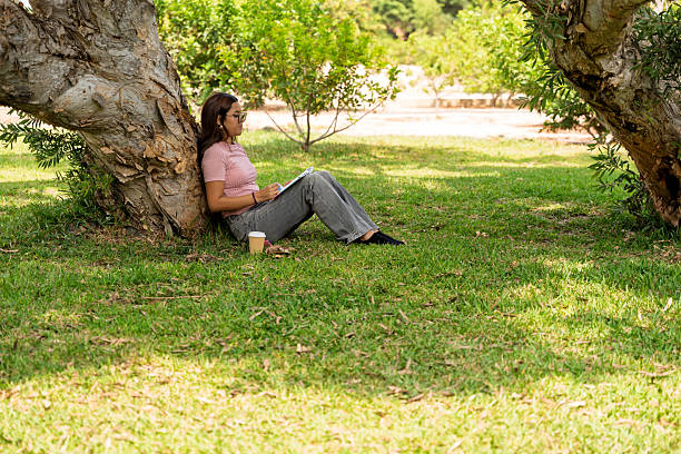 istock Teenage girl studying outdoors in park under tree 2245185755
