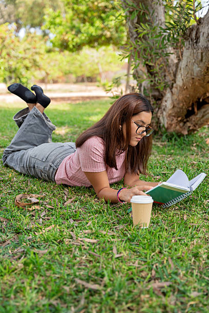 istock Teenage student studying outdoors lying on green grass 2245185776