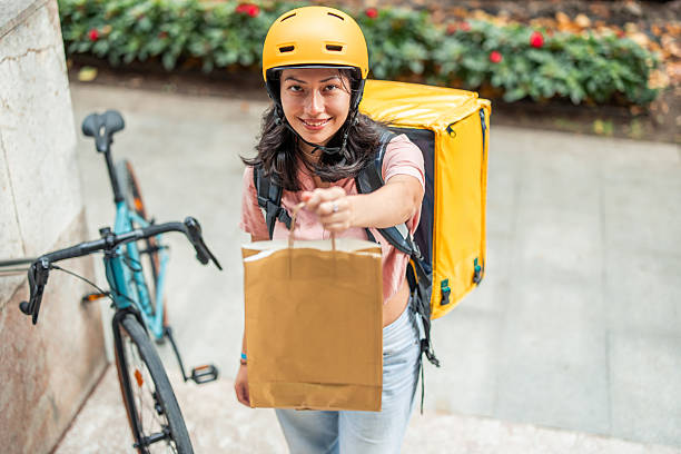 istock Asian female courier delivering food package while smiling 2245188042
