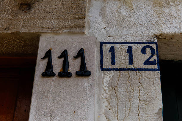 istock Adjacent house numbers 111 and 112 on a textured wall 2245188235