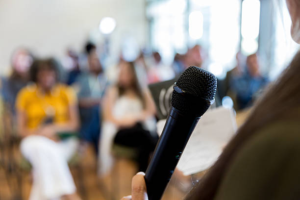 istock Speaker addresses audience during presentation with microphone in hand 2245192459