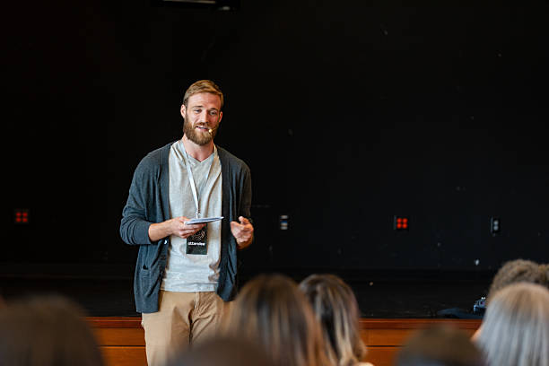 istock Man presenting to an audience, holding papers and speaking 2245192484