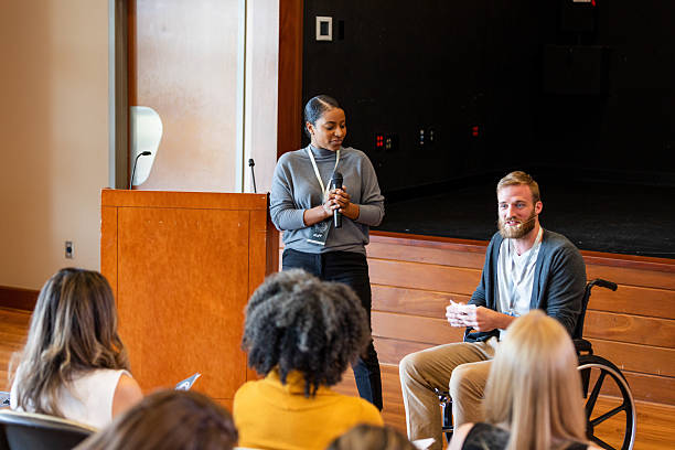 istock Diverse group of people gathered for a discussion with speakers in a modern indoor setting. 2245192494