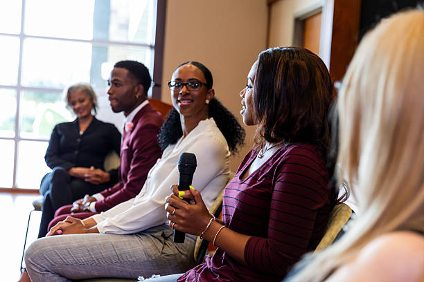 istock Diverse group of people engaged in a panel discussion with a microphone. 2245193674