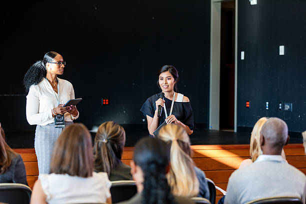 istock Two women presenting to a diverse group of people in a conference setting. 2245193703