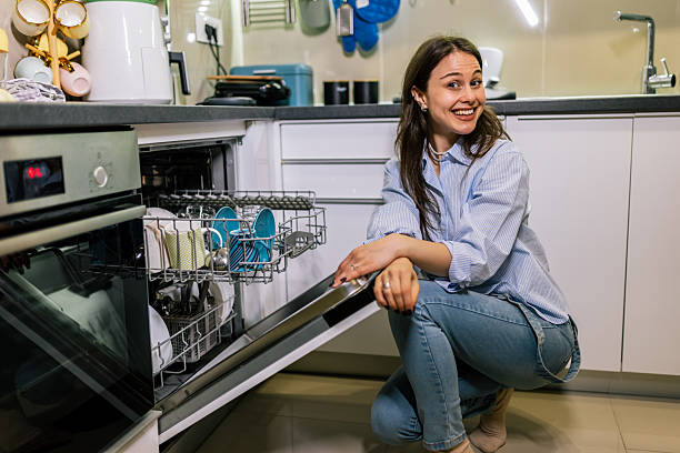 istock Young woman smiling by open dishwasher 2245198528