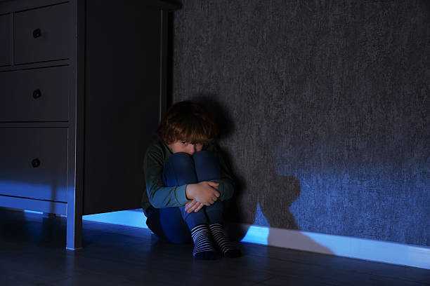 istock Scared boy hiding behind chest of drawers at night 2245205714