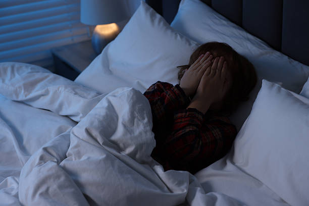 istock Scared boy covering face with hands in bed at night 2245205767