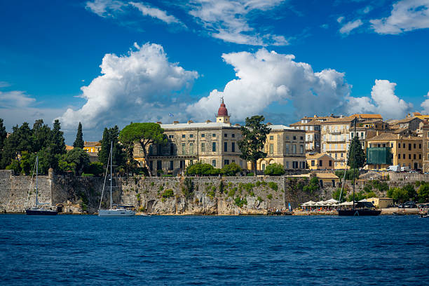 Corfu Old Town historic architecture lining the Ionian Sea under a clear blue sky with white clouds