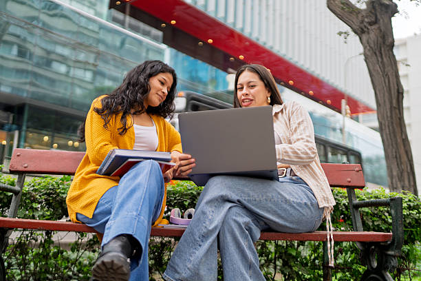istock College students discussing project using laptop outdoors 2245208410