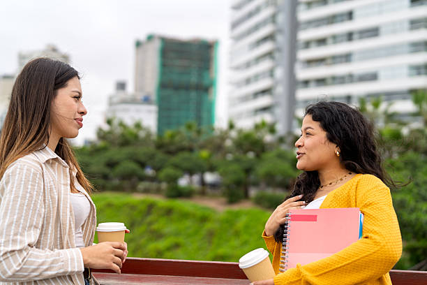 istock Two young adult students talking on campus with coffee cups 2245208495
