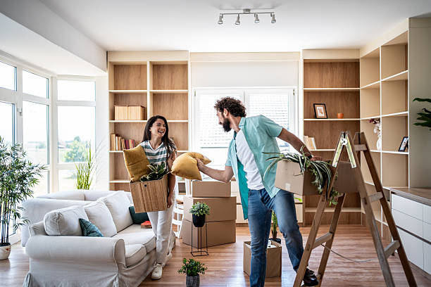 istock Couple moving into new home carrying boxes and plants 2245212874
