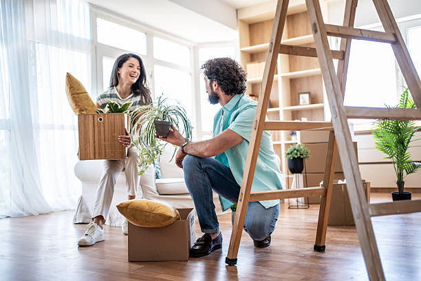istock Young couple unpacking moving box bringing plants into new home 2245212896