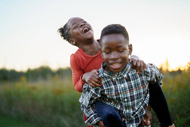 istock Joyful Black Friends Laughing and Playing Outdoors in a Sunny Field 2245213378
