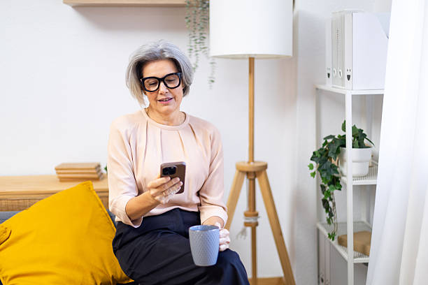 istock Senior woman relaxing on couch using smartphone 2245214381