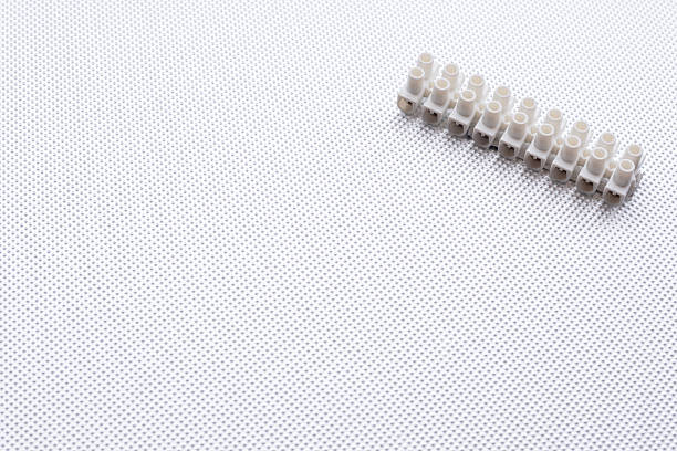 Close-up of a white electrical terminal block on a metallic textured surface, representing connection, energy, and technology in a minimal and clean composition, copy space