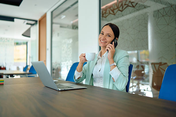 istock Businesswoman talking on phone, drinking coffee in office 2245215321