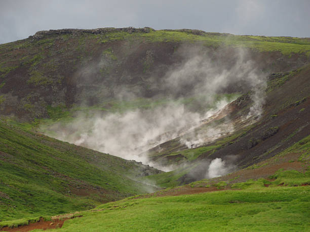 Steaming Geothermal Area on Grassy Dark Hills in Iceland