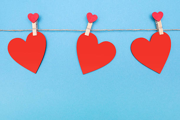 istock Three red hearts are attached to a rope with clothespins on a blue background 2245215577