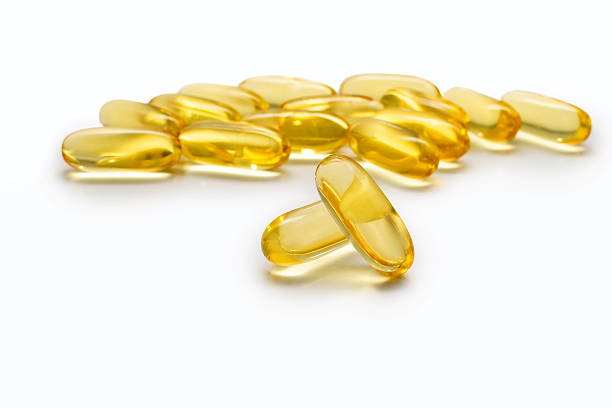 istock Two Omega 3 capsules isolated on a white background and many other capsules on a blurred background 2245215647