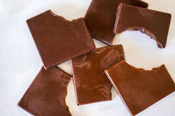 istock Broken milk chocolate squares scattered on white background 2245217970