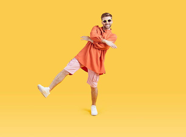 istock Funny young guy in summer casual clothes having fun dancing isolated on yellow background. 2245218420