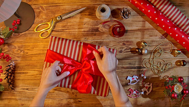 istock Hands tying a red ribbon on a striped gift box 2245219059