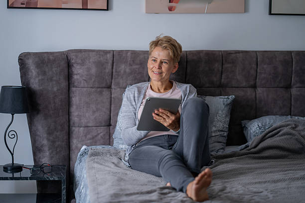 istock Mature woman relaxing on bed using digital tablet 2245219706