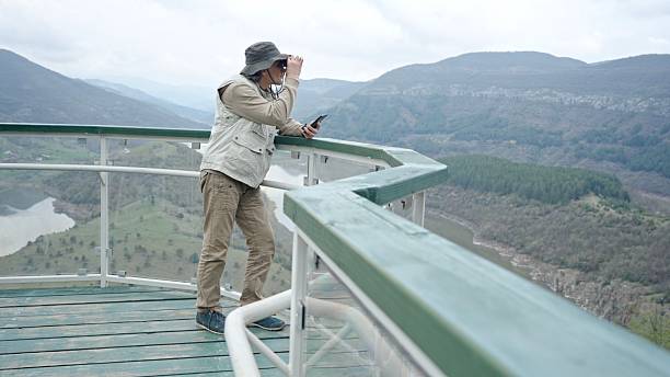 istock Man Birdwatching From Observation Deck With Fjord View 2245220291